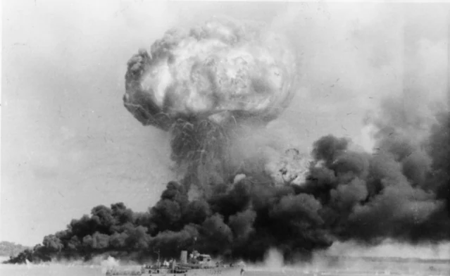 The explosion of MV Neptuna at Stokes Hill Wharf during the first raid, a corvette in the foreground — Australian War Memorial 128108